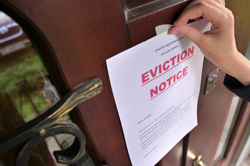 Person Applying Eviction Notice Paper On A Door